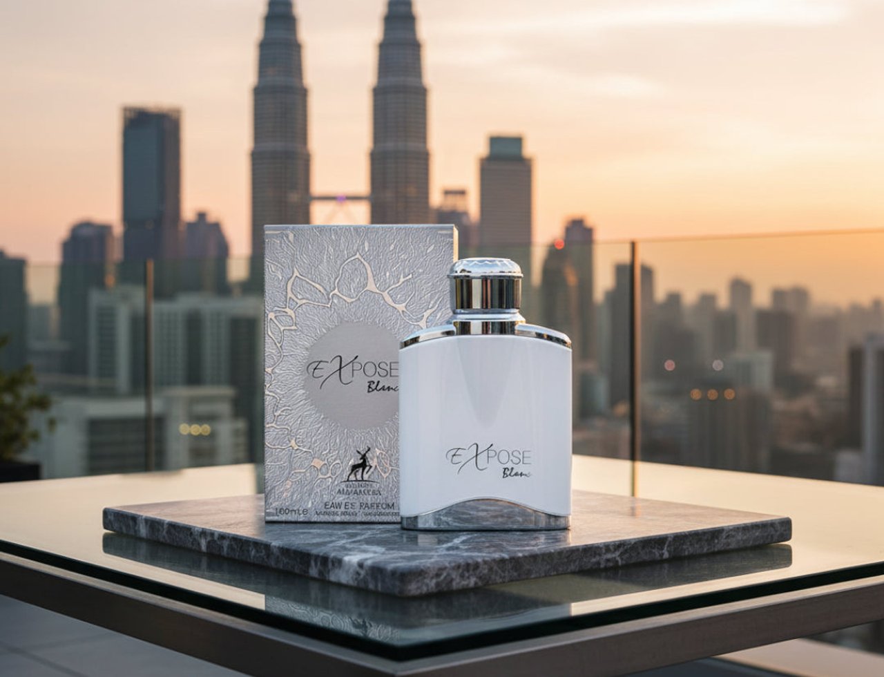 Maison Alhambra Expose Blanc by Maison Alhambra 100ml EDP Men — White perfume bottle and box on a marble slab with Kuala Lumpur skyline at sunset in the background.