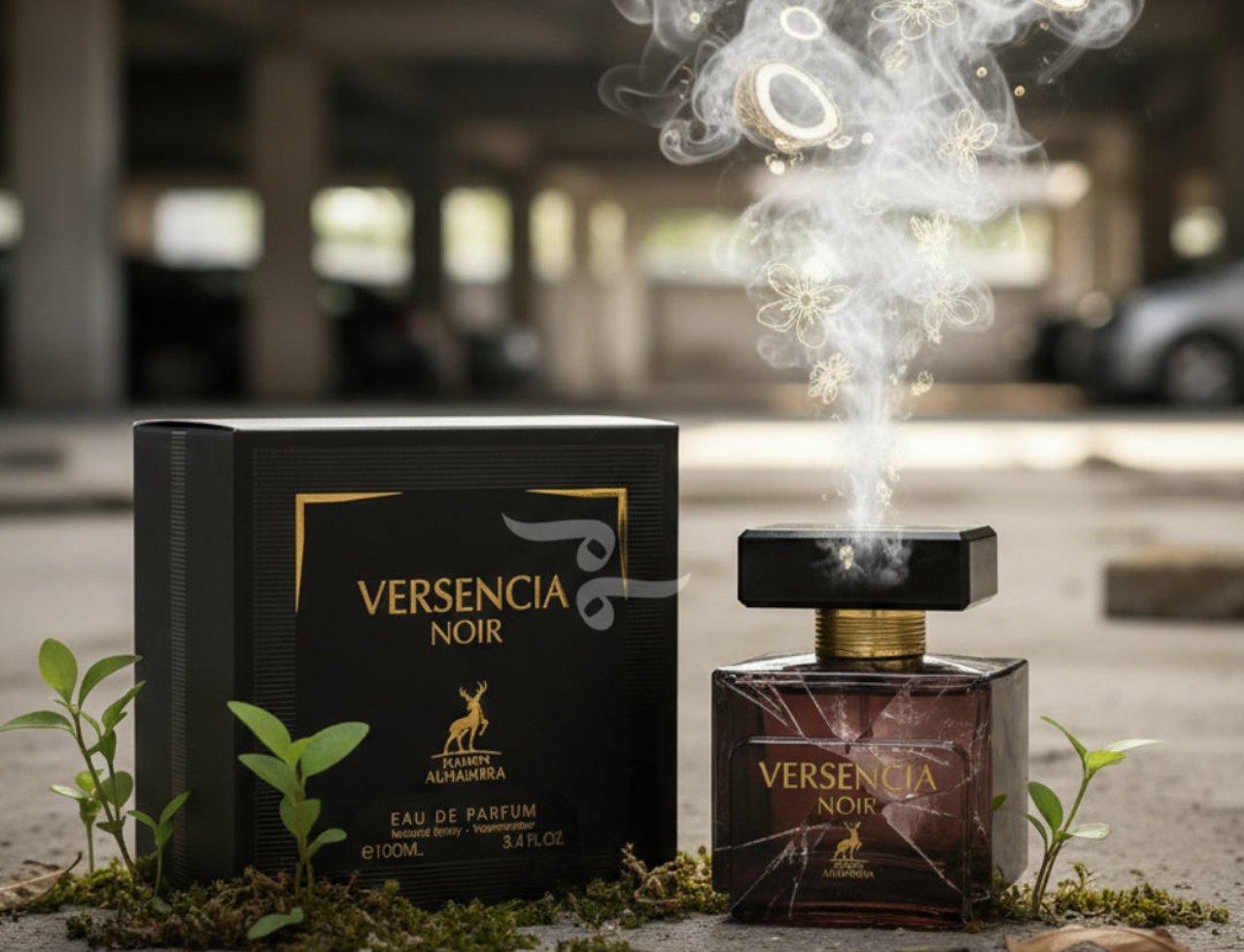 Maison Alhambra Versencia Noir – Black perfume box and marbled glass bottle with gold accents, surrounded by moss and small green plants, with smoke and floral elements rising from the bottle.