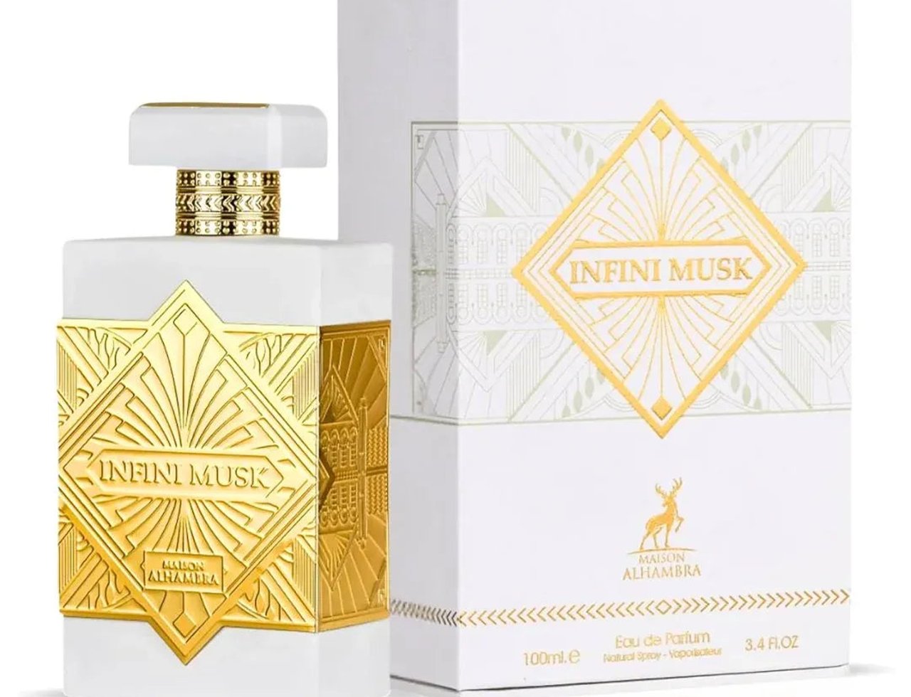 Maison Alhambra Infini Musk – Botol minyak wangi putih dengan perincian geometri emas dan kotak putih sepadan dengan rekaan geometri emas dan logo rusa.
