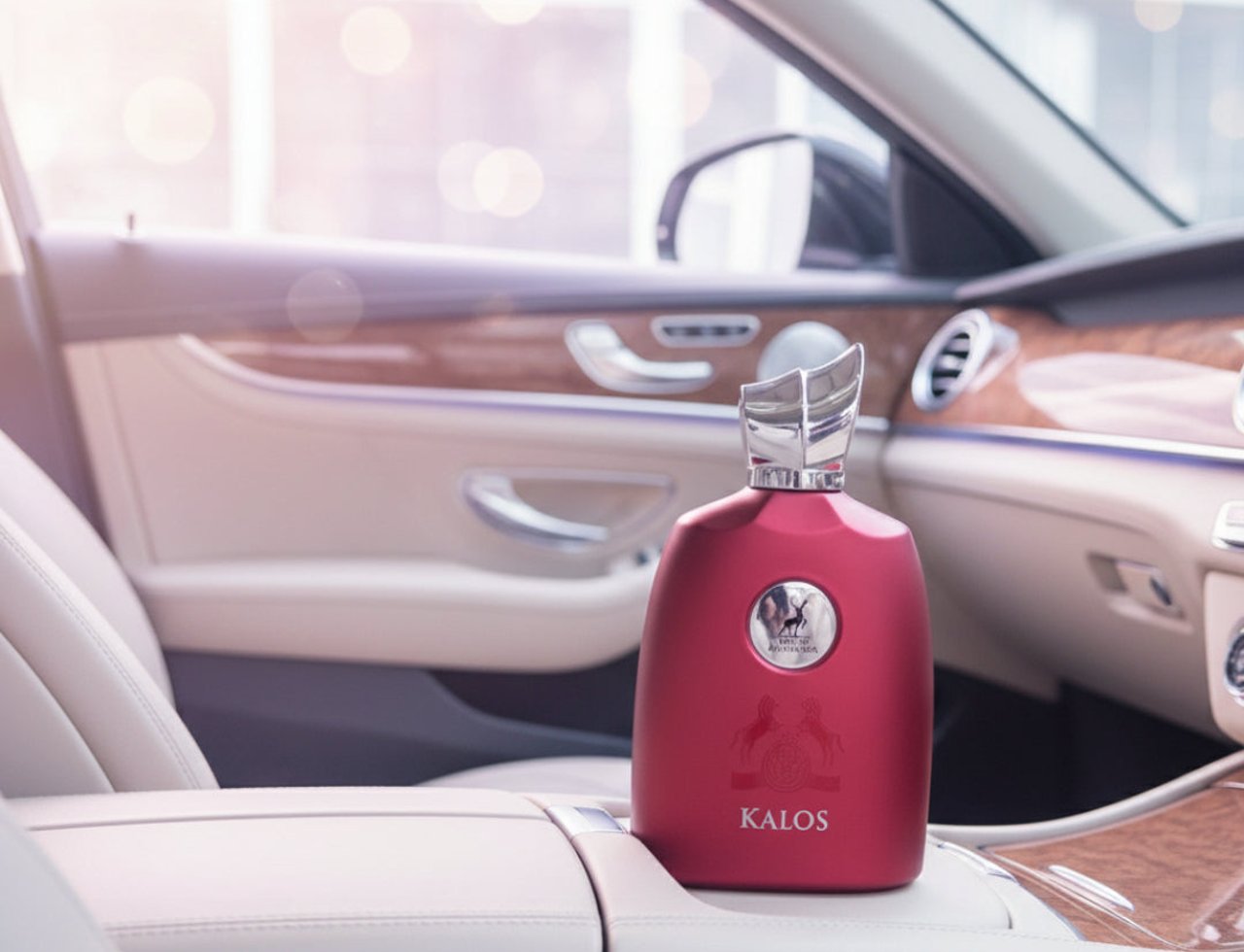 Maison Alhambra Kalos by Maison Alhambra Woman 100ml — Botol minyak wangi merah bertutup perak, diletakkan di atas tempat letak tangan kulit dalaman kereta.