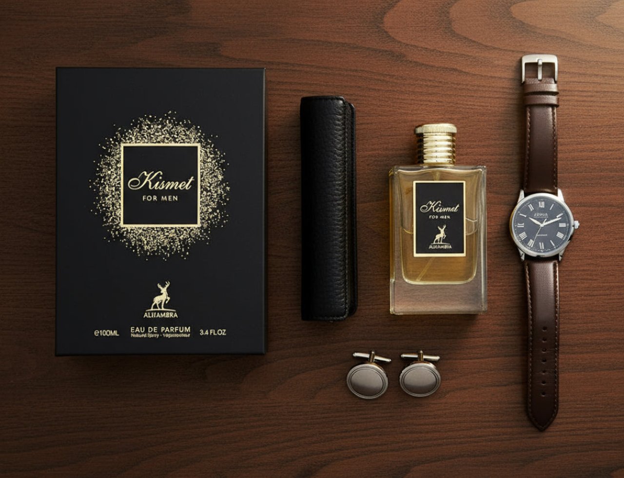 Maison Alhambra Kismet For Men Eau de Parfum — Black gift box with gold glitter, perfume bottle with gold cap, leather case, and brown leather watch on a wooden surface.