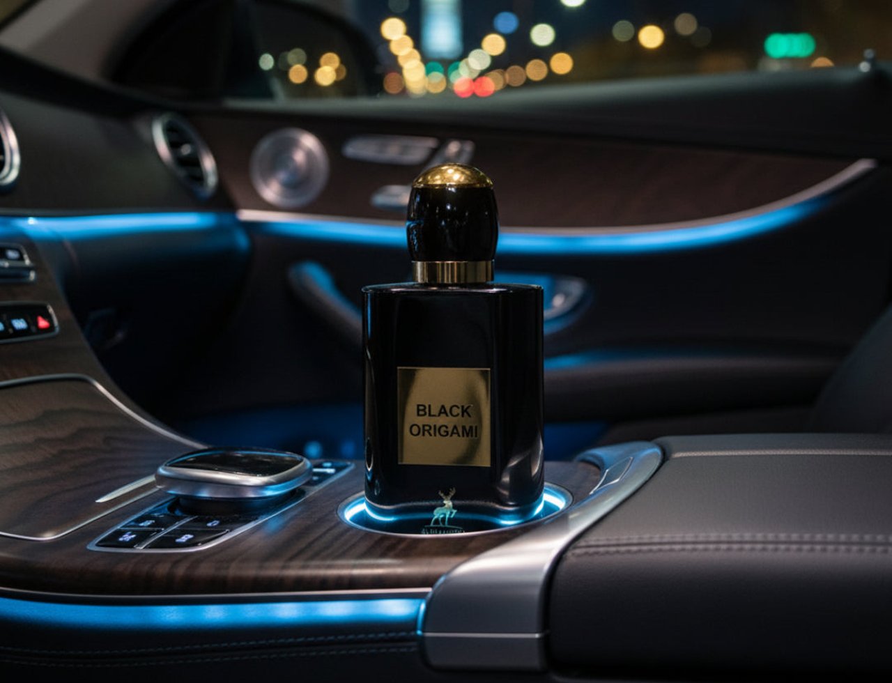 Maison Alhambra Black Origami 100ml EDP — Black perfume bottle with gold cap and label, placed in a car's cup holder with ambient blue lighting at night.