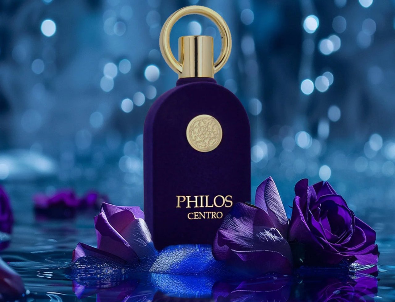 Maison Alhambra Philos Centro — Botol minyak wangi baldu ungu dengan perincian emas, dikelilingi kelopak mawar ungu terapung di atas air dengan lampu bokeh di latar belakang.