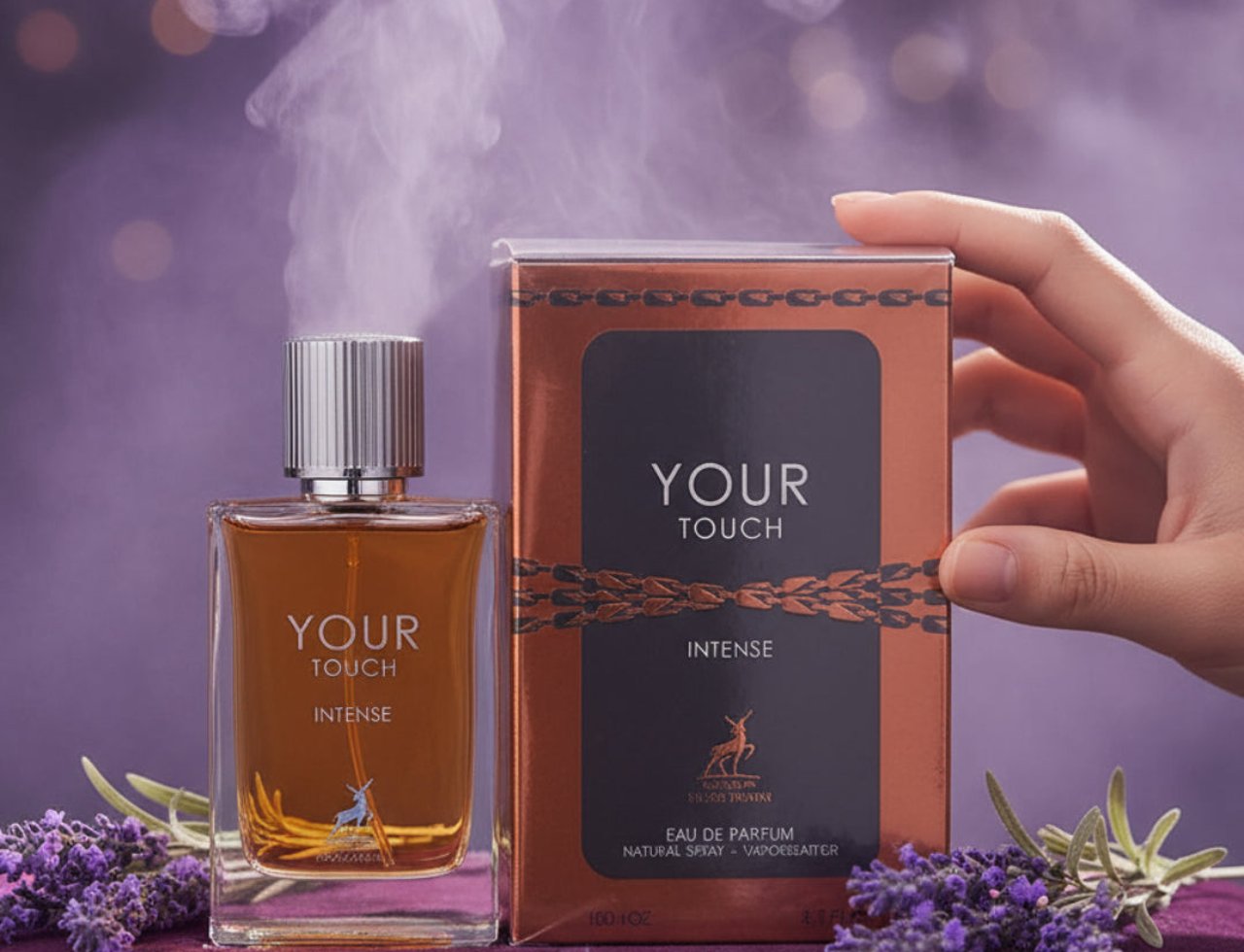 Maison Alhambra Your Touch Intense — Botol minyak wangi kaca berisi cecair perang dan penutup perak berjalur, bersebelahan kotak tembaga dan hitamnya, dengan kuntuman lavender dan kesan asap.