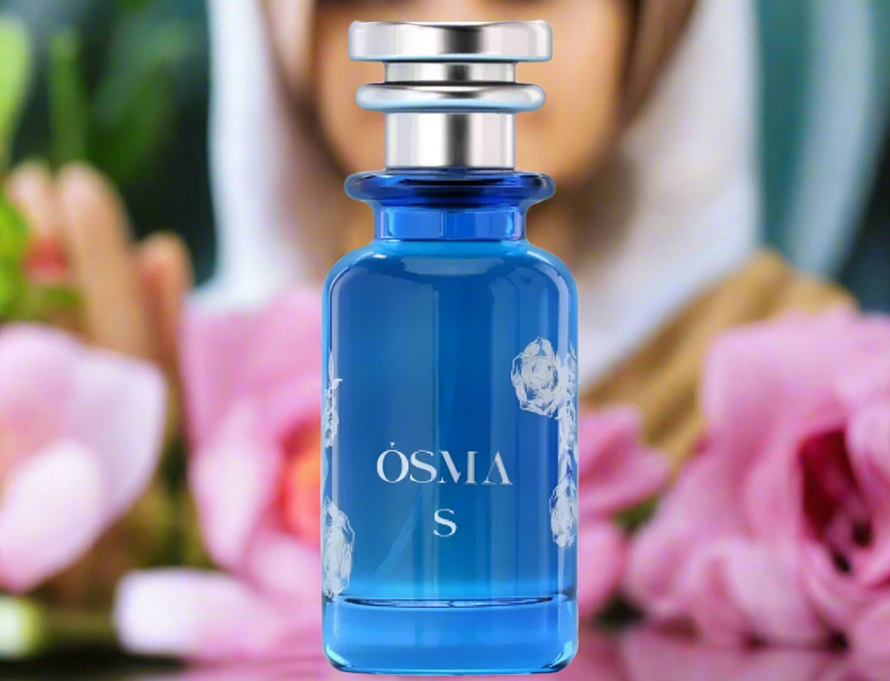 Osma Osma S – Pepper & Sandalwood EDP 150 ml — Blue glass perfume bottle with silver cap, decorated with white floral motifs, set against a soft-focus background of pink roses and a veiled woman.