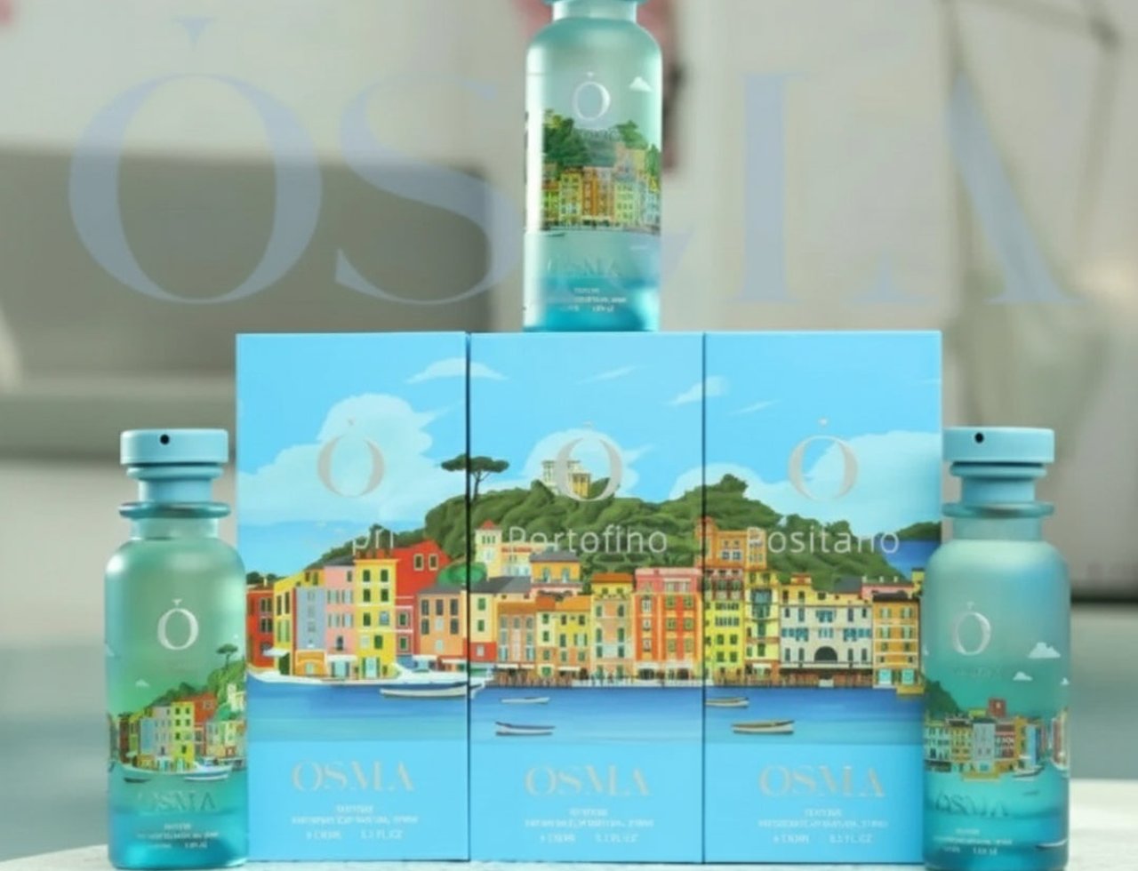 Osma Osma Portofino Summer Purity 150ml EDP — Tiga kotak Osma Portofino Summer Purity EDP disusun sebaris, dengan dua botol di tepi dan satu botol di atas kotak tengah. Kotak dan botol menampilkan ilustrasi Portofino yang berwarna-warni.