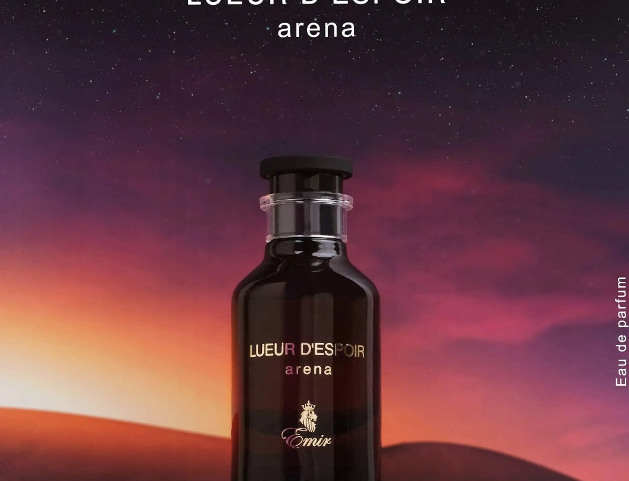 Paris Corner Lueur D Espoir Ambre by Emir Paris Corner 100ml — A dark glass perfume bottle with gold lettering sits on a reflective surface against a desert dune background at sunset with a starry sky above.