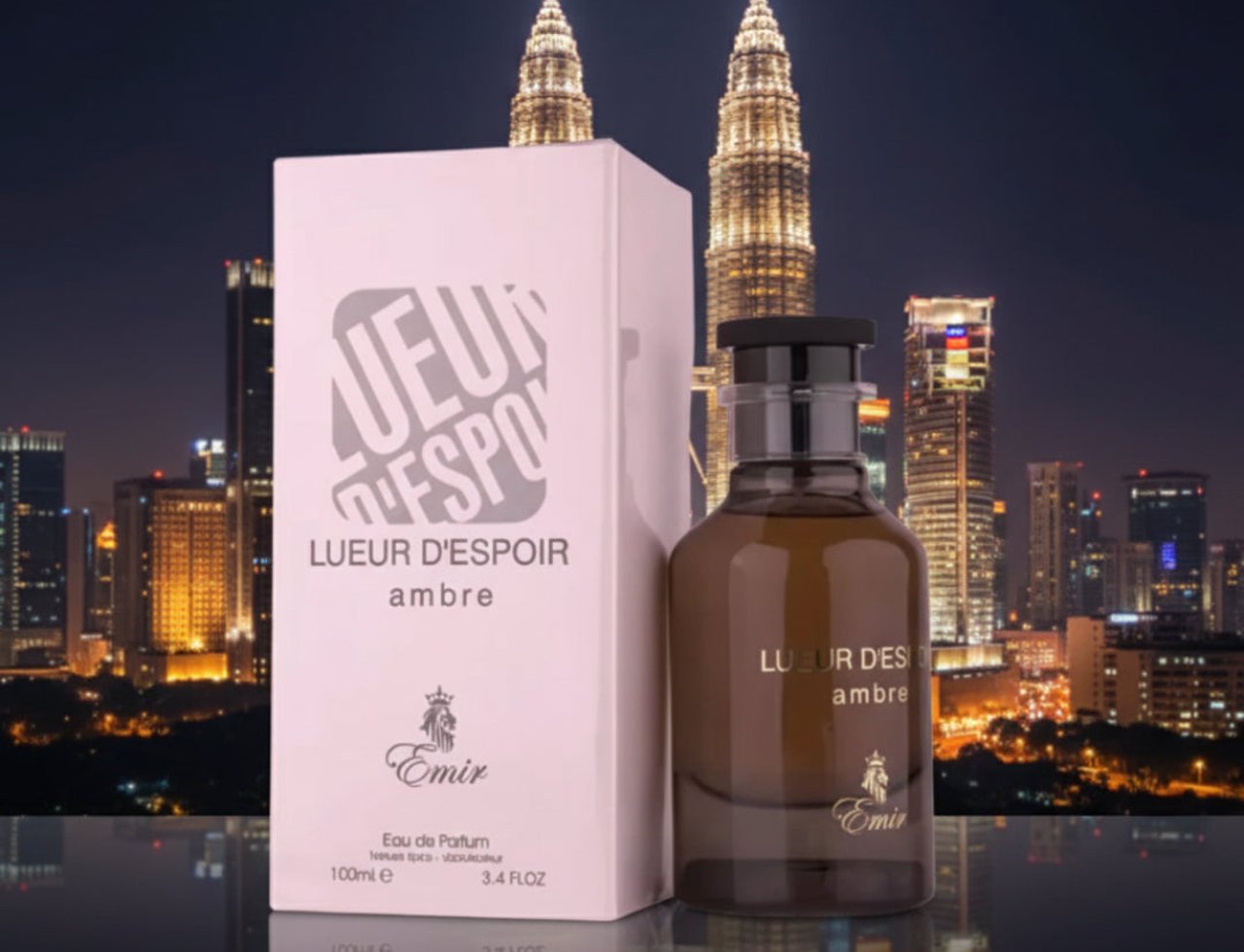Paris Corner Lueur D Espoir Ambre by Emir Paris Corner 100ml — Kotak minyak wangi putih dan botol kaca ambar berlatarkan pemandangan bandar malam dengan pencakar langit yang diterangi.