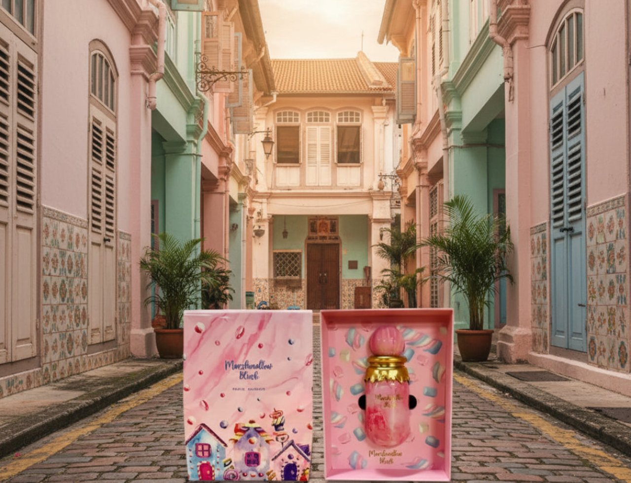 Paris Corner Marshmallow Blush by Paris Corner for Her 100ml — Perfume bottle and its box displayed on a cobblestone street with colorful shophouses in the background, surrounded by marshmallow candies.