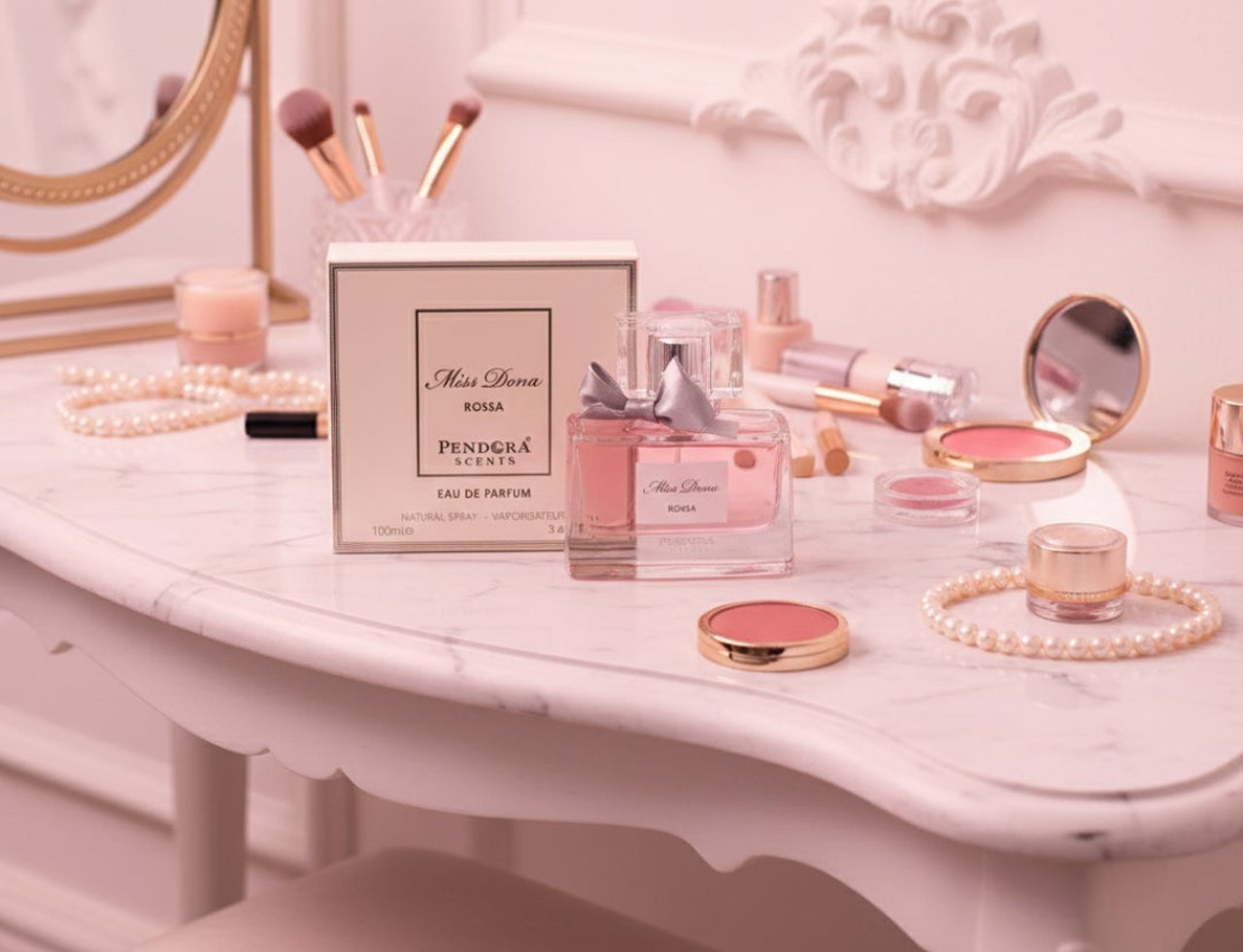 Paris Corner Miss Dona by Paris Corner 100ml Women — Botol minyak wangi merah jambu bertali reben perak terletak di atas meja solek marmar bersebelahan kotaknya, dikelilingi alat solek dan aksesori mutiara.