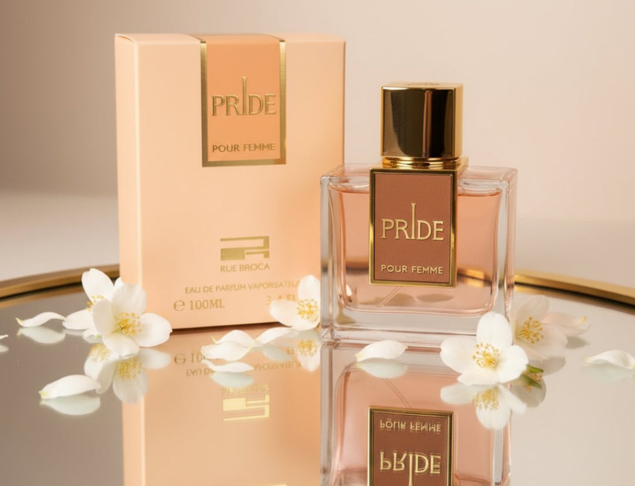Rue Broca Pride Pour Femme Rue Broca 100ml EDP — Kotak berwarna pic dan botol minyak wangi kaca jernih bertutup dan berlabel emas, dikelilingi bunga melur putih dan kelopak di atas permukaan memantul.
