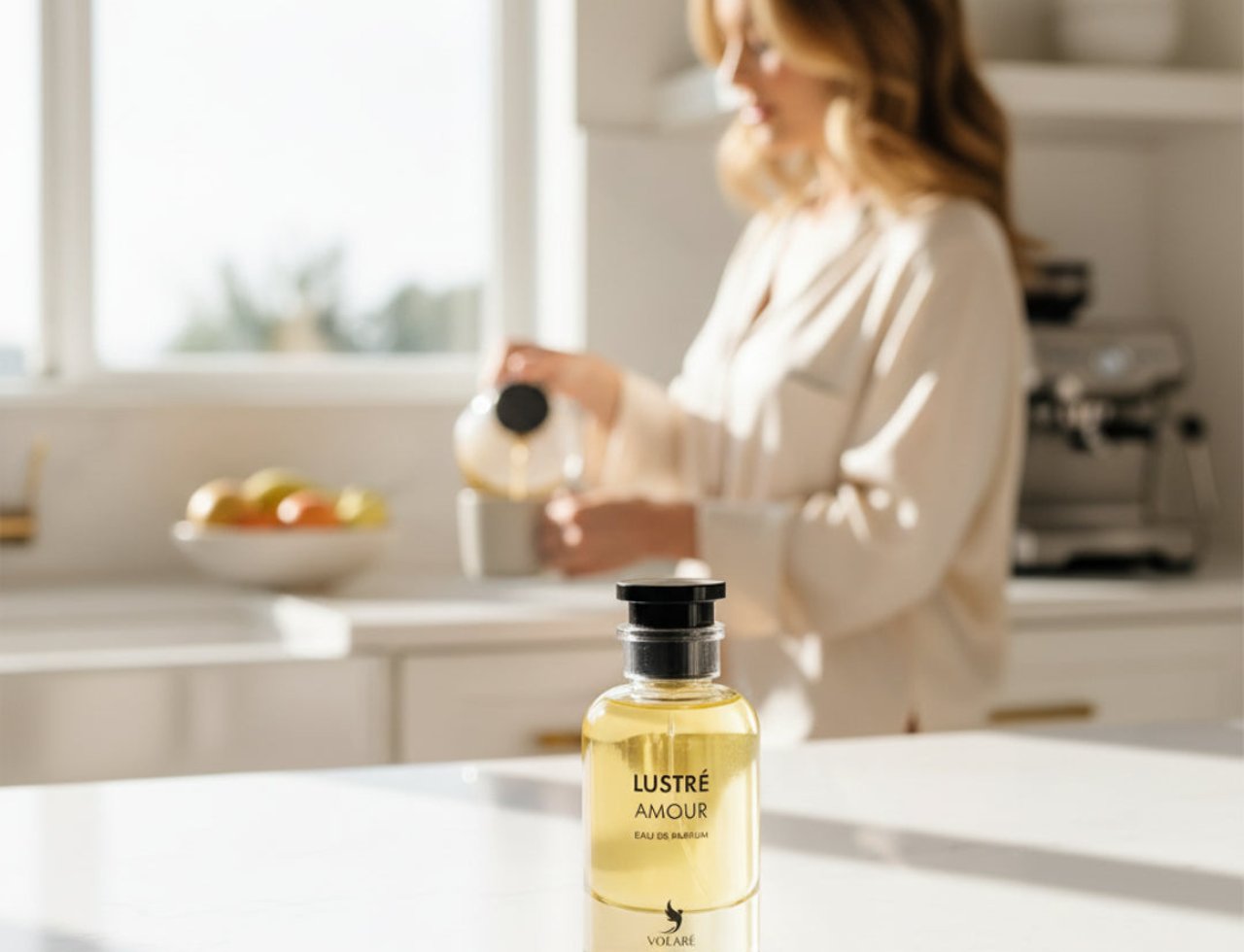 Volare Lustre Amour – A clear glass perfume bottle with a black cap sits on a white marble surface, with a woman pouring liquid in the background.