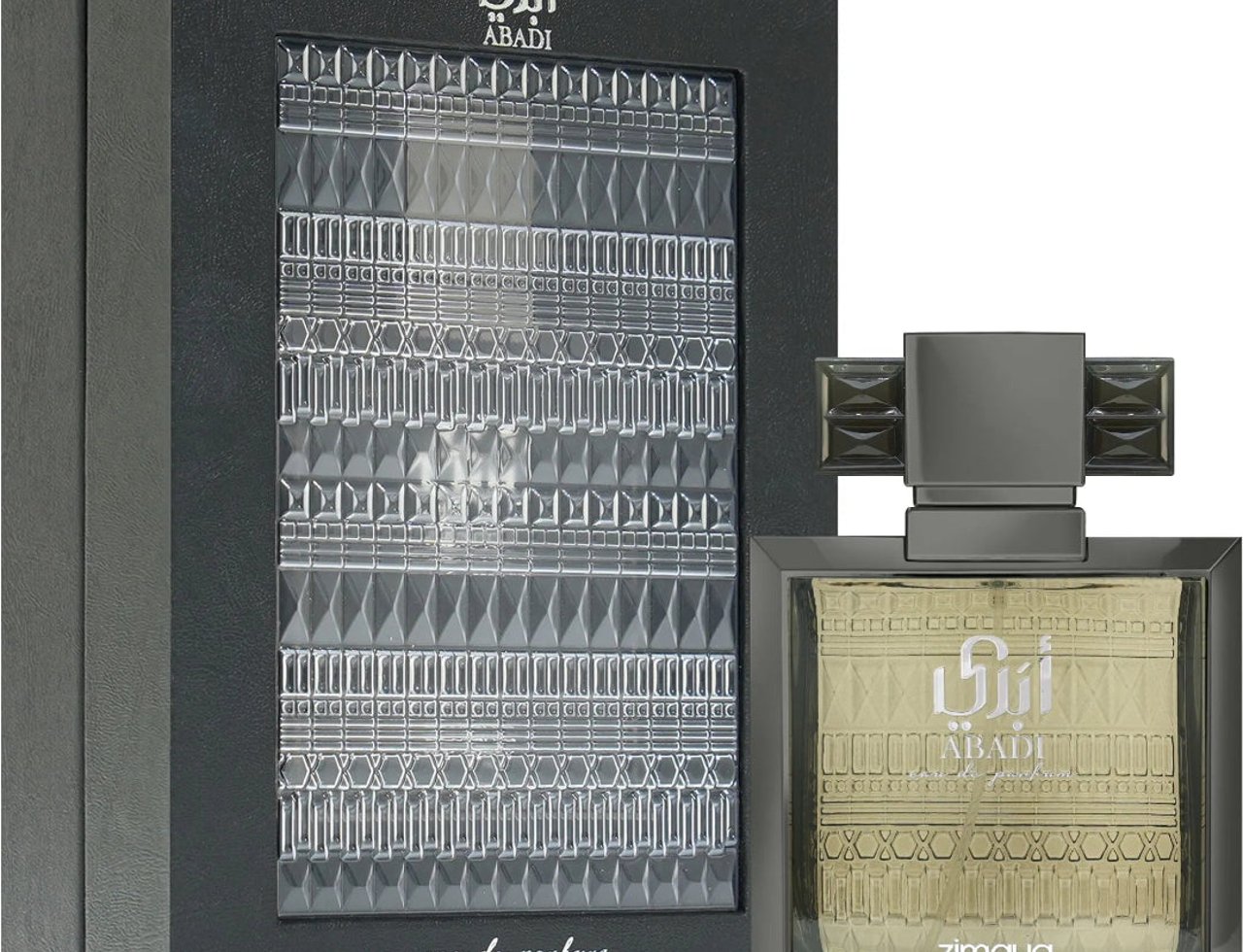 Zimaya Abadi Saga by Zimaya EDP 100 ml Men — Kotak hadiah hitam dengan tingkap lutsinar bertekstur, memaparkan botol minyak wangi segi empat kelabu gelap dengan cecair keemasan dan penutup kelabu gelap.