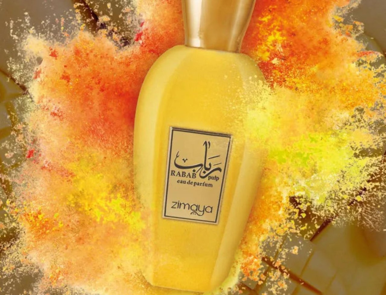 Zimaya Rabab Pulp by Zimaya 100 ml EDP Unisex — Yellow perfume bottle with a gold cap, surrounded by a vibrant explosion of orange and yellow powder, with a hint of sliced mango in the background.