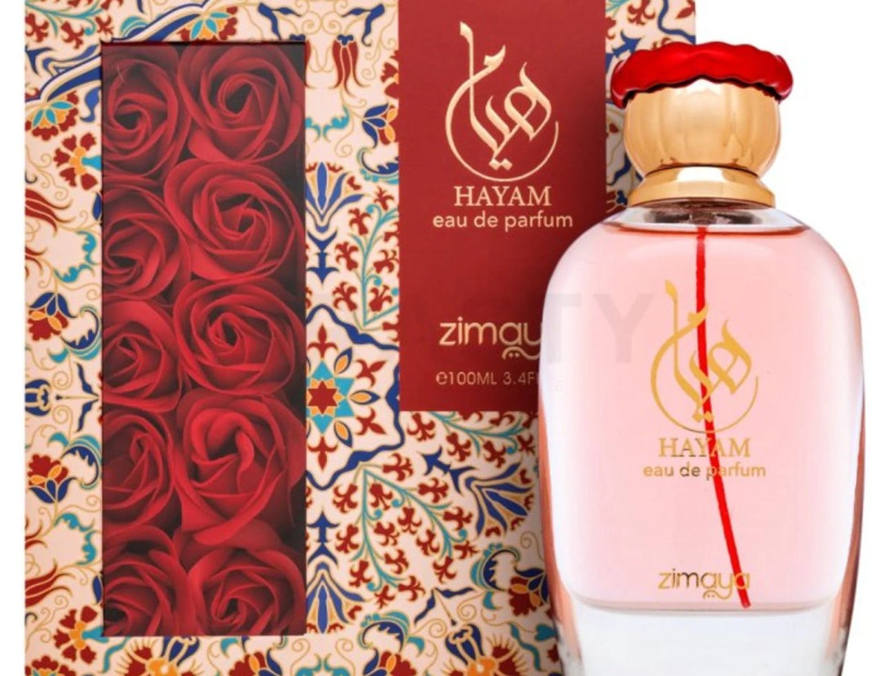 Zimaya Hayam Eau de Parfum 100ml — Botol minyak wangi merah jambu dengan penutup emas dan logo tulisan Arab, bersebelahan kotak corak merah dan emas menampilkan bunga ros merah.