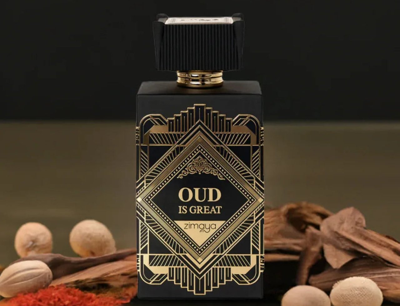 Zimaya Oud Is Great by Zimaya 100ml EDP Unisex — Black perfume bottle with gold geometric design, gold cap, surrounded by oud wood chips, nutmeg, and red spice powder.