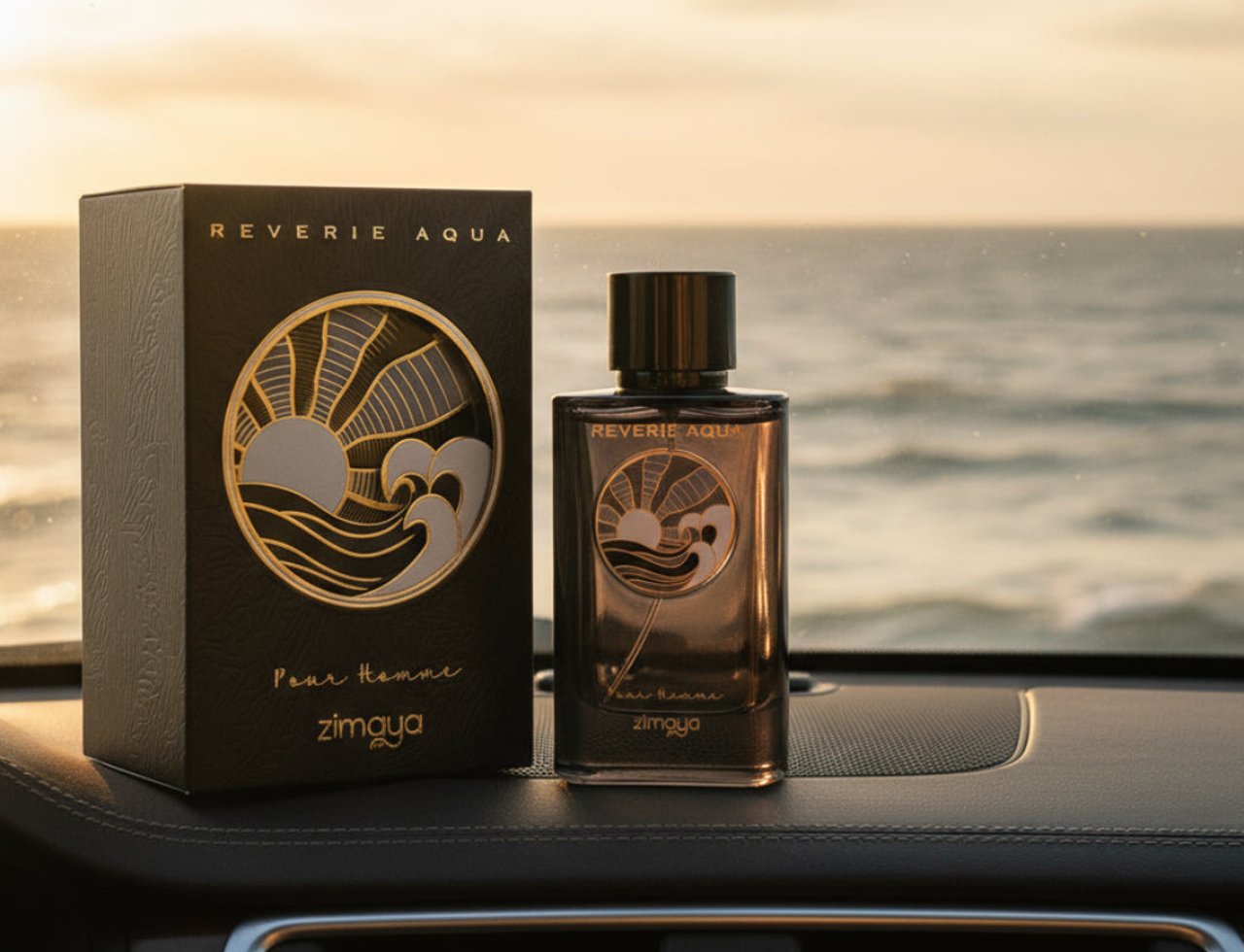 Zimaya Reverie Aqua by Zimaya 100ml EDP Men — Black textured box and glass bottle with gold sun and wave design, placed on car dashboard with ocean sunset background