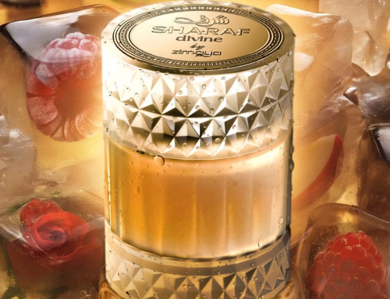Zimaya Sharaf Divine By Zimaya 100 ml Extrait Unisex — Botol minyak wangi bertutup emas dikelilingi ketulan ais berisi raspberi dan mawar, dengan hirisan lemon di latar belakang.