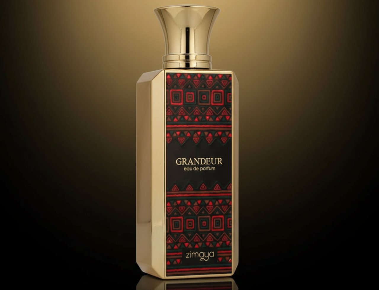 Zimaya Grandeur 100ml EDP for Unisex — Botol emas dengan label corak merah dan hitam berhias, tertulis 'GRANDEUR eau de parfum' dan 'zimaya'. Botol mempunyai penutup emas dan terpantul pada permukaan gelap berlatar belakang gradien.