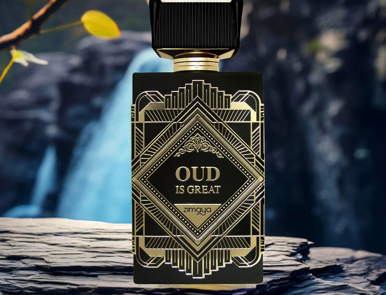 Zimaya Oud Is Great by Zimaya 100ml EDP Unisex — Botol minyak wangi hitam dan emas gaya art deco dengan reka bentuk geometri berhias, diletakkan di atas batu bertekstur gelap dengan latar belakang air terjun dan tumbuhan yang kabur.