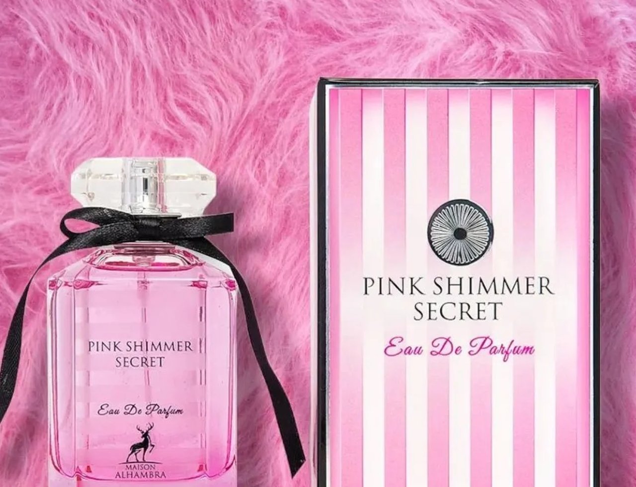 Maison Alhambra Pink Shimmer Secret 100ml — Botol kaca jernih berisi cecair merah jambu, diikat dengan reben hitam, bersebelahan kotak berjalur merah jambu dan putih.