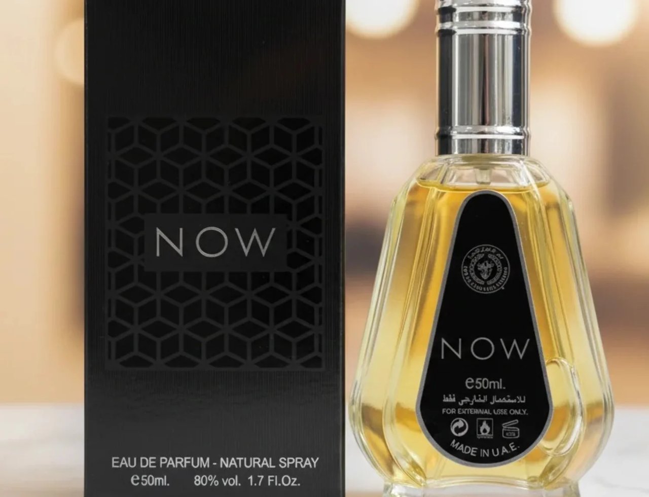 Ard Al Zaafaran Rave Now 50ml EDP for Men — Black textured box with geometric pattern and 'NOW' logo next to a clear glass perfume bottle with yellow liquid and silver cap.