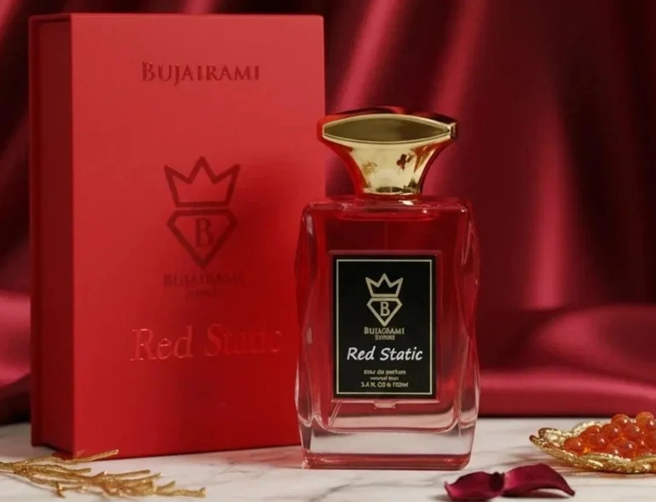 Bujairami Red Eclipse by Bujairami 100ml EDP — Red perfume bottle with gold cap, next to its red presentation box, on a marble surface with gold accents and rose petals.