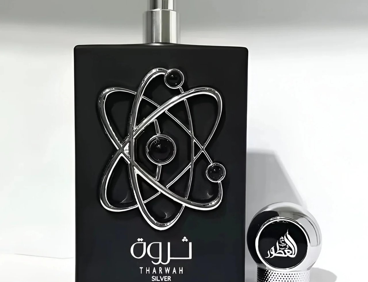 Lattafa Pride Tharwah Silver — Botol minyak wangi hitam dengan rekaan atom perak dan penutup sepadan, dipamerkan di latar belakang putih.