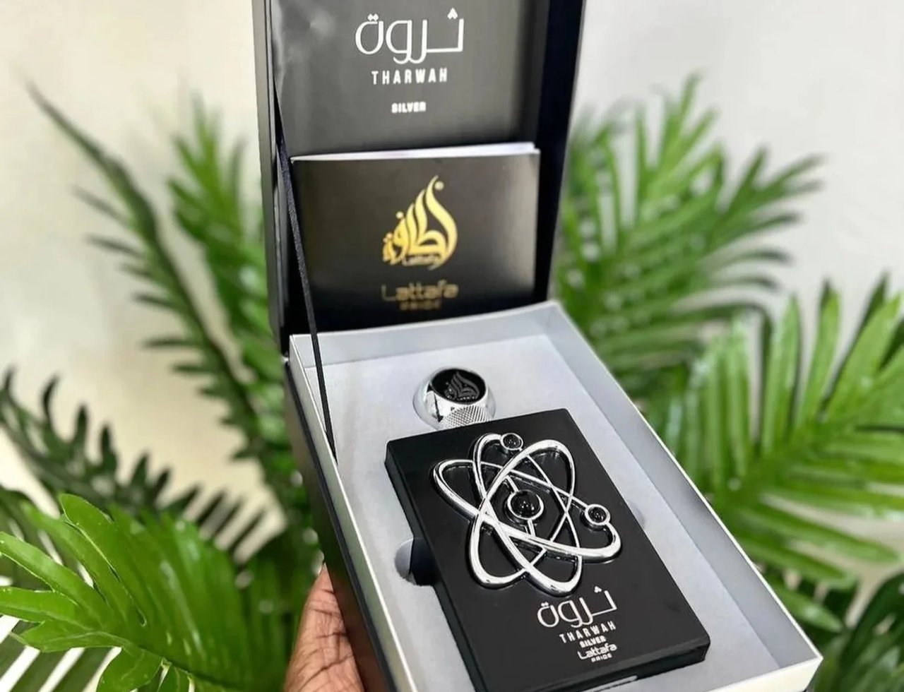 Lattafa Pride Tharwah Silver by Lattafa Pride 100ml EDP — Black gift box open, showing a black perfume bottle with a silver atom design, a silver cap, and a booklet.