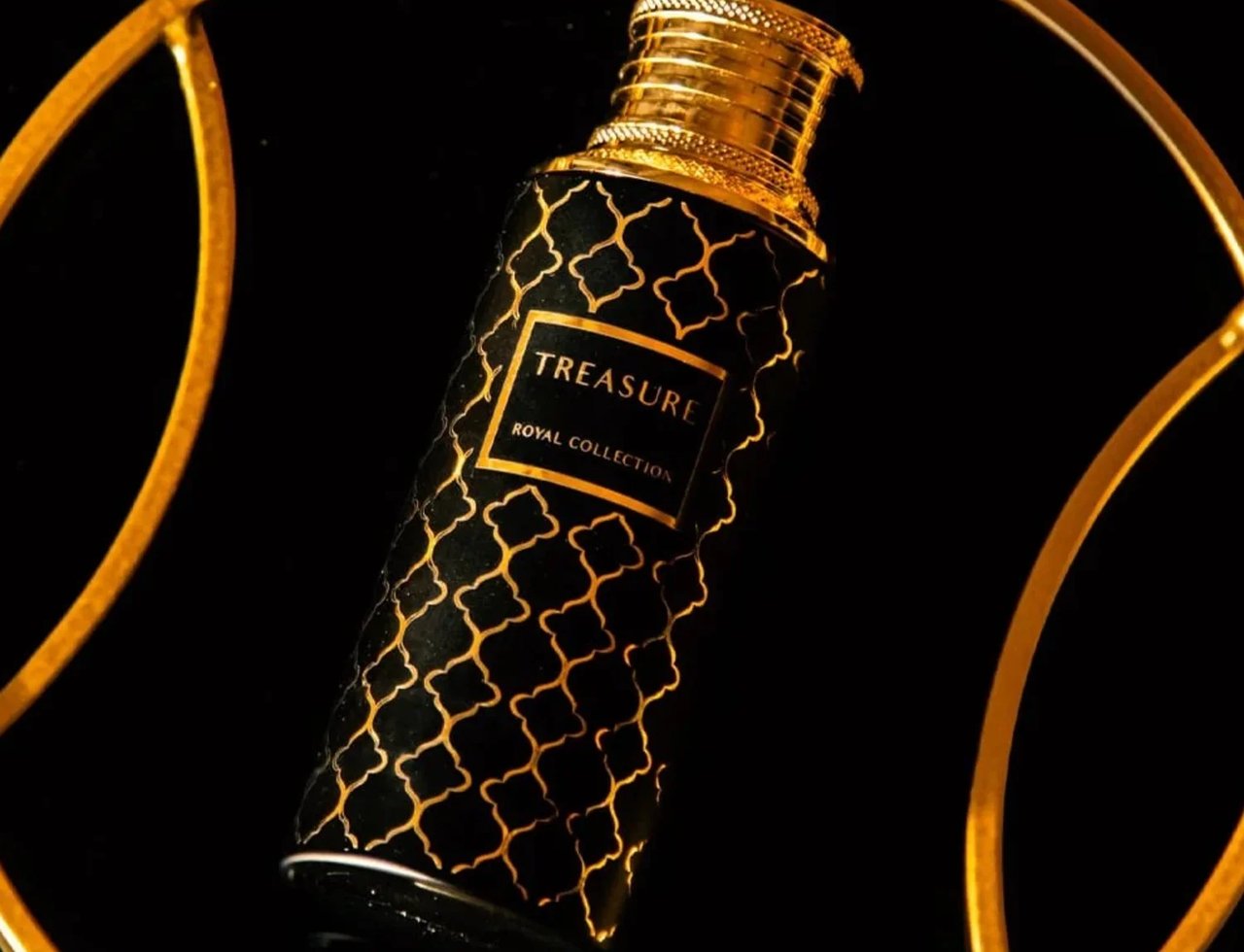 Maison Asrar Treasure by Maison Asrar 100ml EDP Unisex — Botol hitam corak geometri emas dan penutup emas, dipamerkan dalam bingkai bulat emas berlatar belakang hitam.