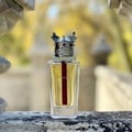 Lattafa Dynasty by Lattafa 100ml EDP Unisex — Clear glass perfume bottle with gold crown cap, red stripe inside, on a stone ledge with blurred background.