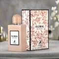 Maison Alhambra Floral Bloom — A light pink rectangular perfume bottle with a rounded cap sits next to its matching floral-patterned box on a marble surface. | Maison Alhambra Floral Bloom — Botol minyak wangi berbentuk segi empat berwarna merah jambu muda dengan penutup bulat terletak di sebelah kotak bercorak bunga