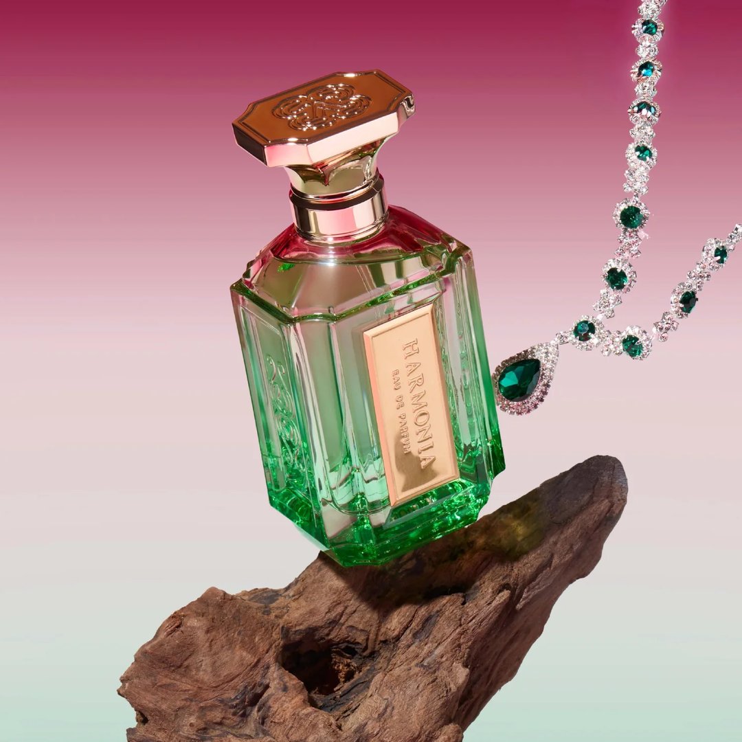 Velixir Harmonia Velixir Parfums 100ml for Unisex — Green faceted glass perfume bottle with gold cap, balanced on driftwood, with a diamond and emerald necklace | Velixir Harmonia Velixir Parfums 100ml for Unisex — Botol kaca hijau berfaset dengan penutup emas, di atas kayu hanyut, dengan kalung berlian dan zamrud