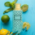 Maison Asrar Imperial by Maison Asrar 100ml EDP Unisex — Botol teal berpenutup emas dan corak geometri, dikelilingi daun pudina segar, limau gedang sebiji, dan hirisan lemon di atas latar biru.