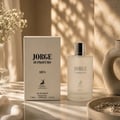 Maison Alhambra Jorge Di Profumo Aqua — A white perfume box and a frosted glass bottle of Jorge Di Profumo Aqua perfume are displayed on a marble surface with soft lighting and shadows. | Maison Alhambra Jorge Di Profumo Aqua — Peti minyak wangi putih dan botol kaca beku minyak wangi Jorge Di Profumo Aqua dipamerkan