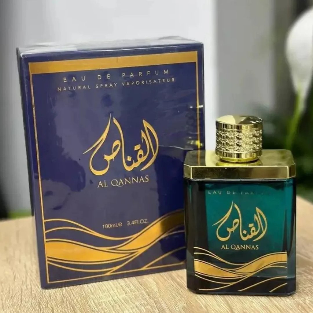 Ard Al Zaafaran Al Qannas Eau De Parfum 100ml — A dark blue box with gold Arabic calligraphy and wavy lines sits next to a square, dark green glass perfume bottle with a gold cap. | Ard Al Zaafaran Al Qannas Eau De Parfum 100ml — Kotak biru gelap dengan kaligrafi Arab emas dan garisan berombak terletak di sebelah