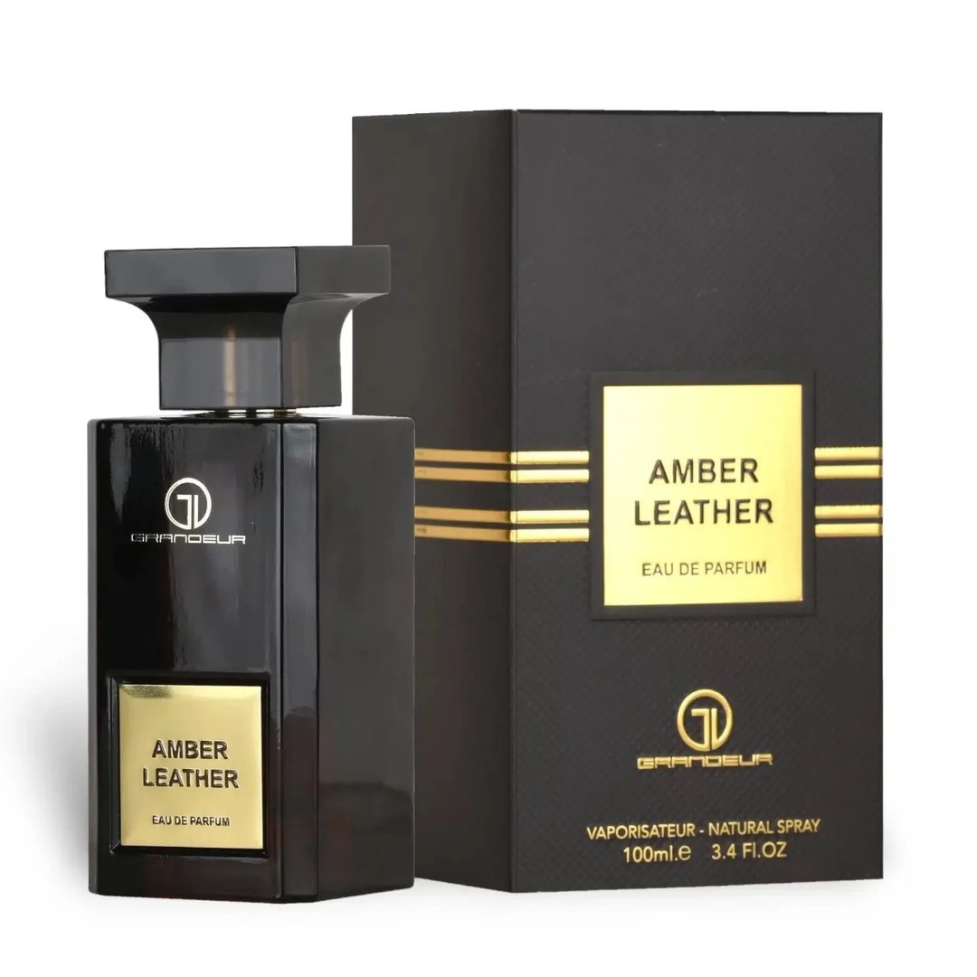 Grandeur Amber Leather 100ml by Grandeur Perfumes — A dark, rectangular perfume bottle with a gold label sits next to its matching black and gold striped box against a white background. | Grandeur Amber Leather 100ml oleh Grandeur Perfumes — Botol minyak wangi segiempat gelap dengan label emas duduk di sebelah kotak