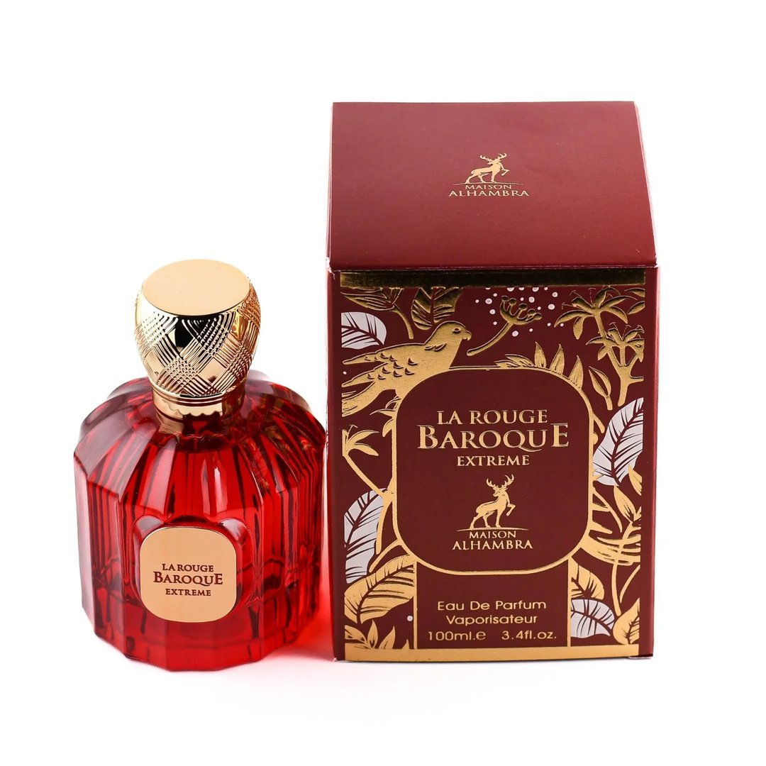 Maison Alhambra Baroque Rouge Extrait 100ml by Maison Alhambra — Red faceted glass perfume bottle with gold cap next to its red and gold decorative box, featuring a bird and deer motif. | Maison Alhambra Baroque Rouge Extrait 100ml by Maison Alhambra — Botol minyak wangi kaca merah berfaset dengan penutup emas di