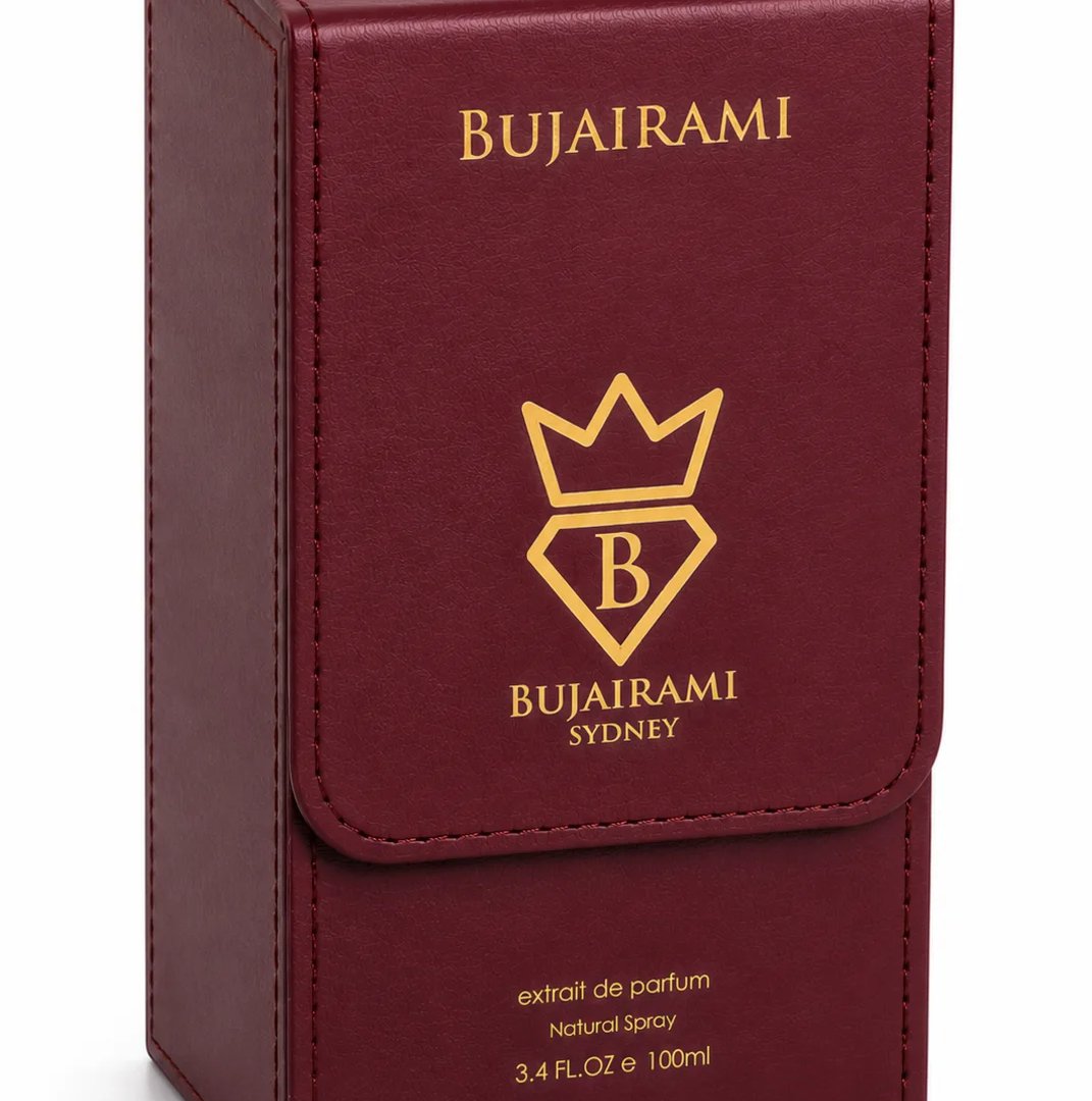 Bujairami Cartel by Bujairami 100ml Extrait — A maroon leather-like box with gold lettering and a crown logo with a 'B' inside a diamond. The box has a flap closure and text indicating 'extrait de parfum', 'Natural Spray', and '3.4 FL.Oz e 100ml'.
