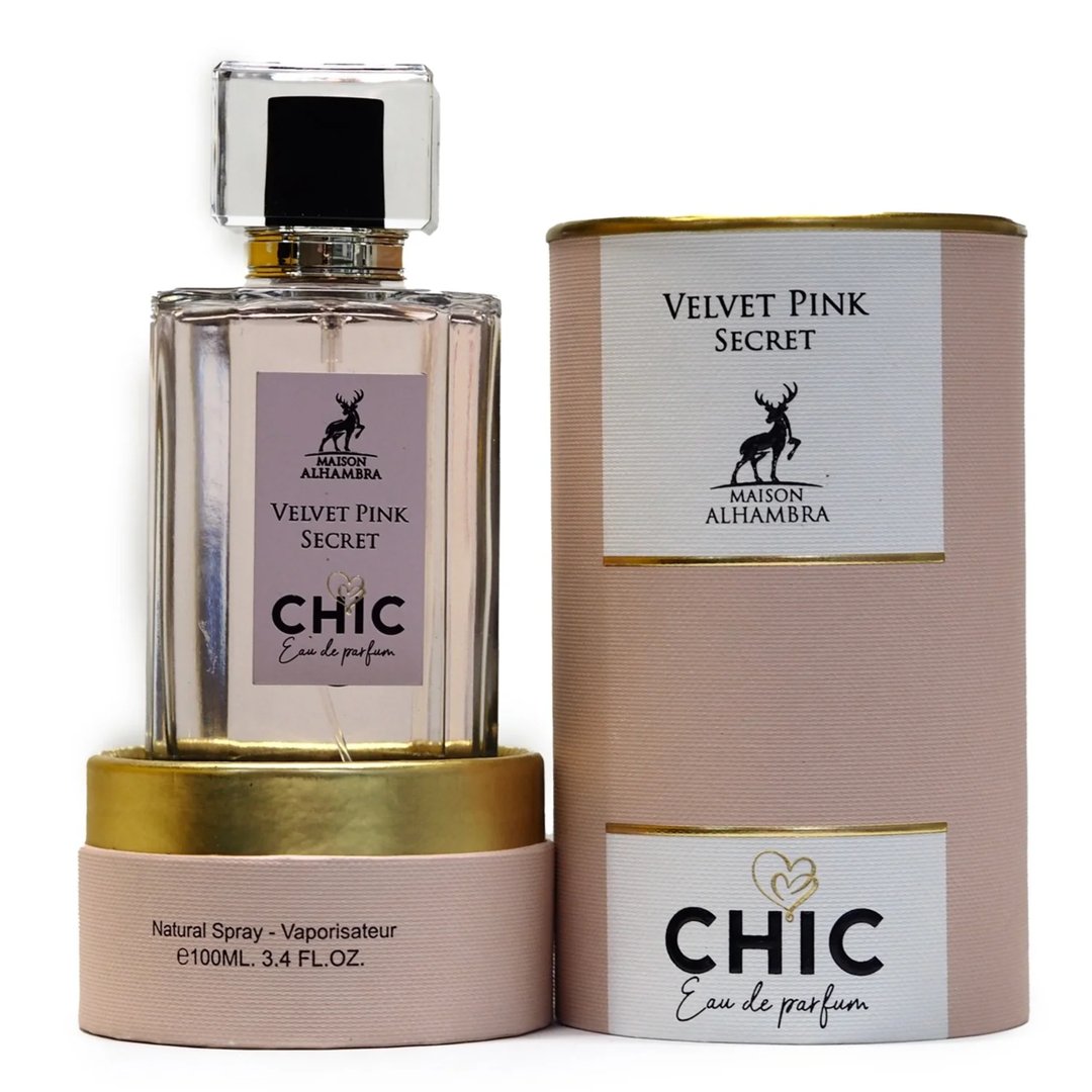Maison Alhambra Chic Velvet Pink Secret for Women 100ml — A clear glass perfume bottle with a gold base and a pink cylindrical box, both featuring a deer logo and text. | Maison Alhambra Chic Velvet Pink Secret for Women 100ml — Botol minyak wangi kaca jernih dengan tapak emas dan kotak silinder merah jambu