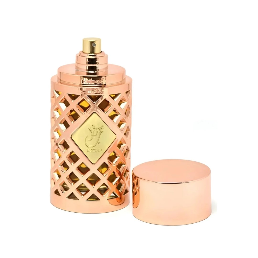 Ard Al Zaafaran Jazzab Gold by Ard Al Zaafaran Eau De Parfum 100ml — Rose gold geometric patterned perfume bottle with a gold emblem and cap removed, revealing amber liquid inside. | Ard Al Zaafaran Jazzab Gold by Ard Al Zaafaran Eau De Parfum 100ml — Botol minyak wangi corak geometri emas ros dengan lambang emas dan