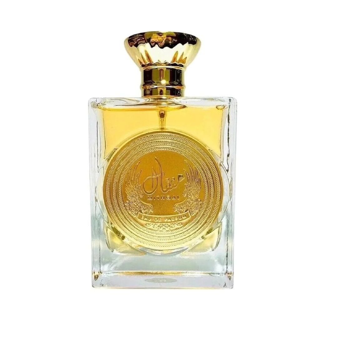 Ard Al Zaafaran Mithqal 100ml by Ard Al Zaafaran — A clear glass perfume bottle with a gold cap and a large circular gold emblem on the front, containing Arabic script and winged designs. The liquid inside is golden yellow. | Ard Al Zaafaran Mithqal 100ml oleh Ard Al Zaafaran — Botol minyak wangi kaca jernih dengan