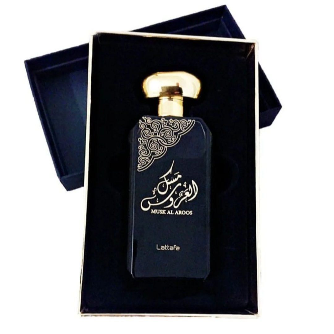 Lattafa Musk Al Aroos by Lattafa 80ml EDP — A dark blue perfume bottle with gold Arabic calligraphy and 'MUSK AL AROOS' text, presented in an open dark blue gift box with a gold trim. | Lattafa Musk Al Aroos by Lattafa 80ml EDP — Botol minyak wangi biru gelap dengan kaligrafi Arab emas dan teks 'MUSK AL AROOS'