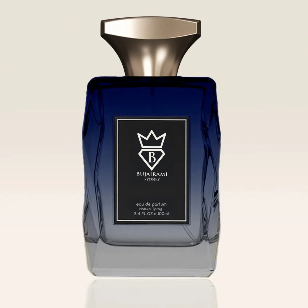 Bujairami New York by Bujairami Eau de Parfum 100ml — A blue and grey gradient glass perfume bottle with a gold cap and a black label featuring a white crown and 'B' logo.