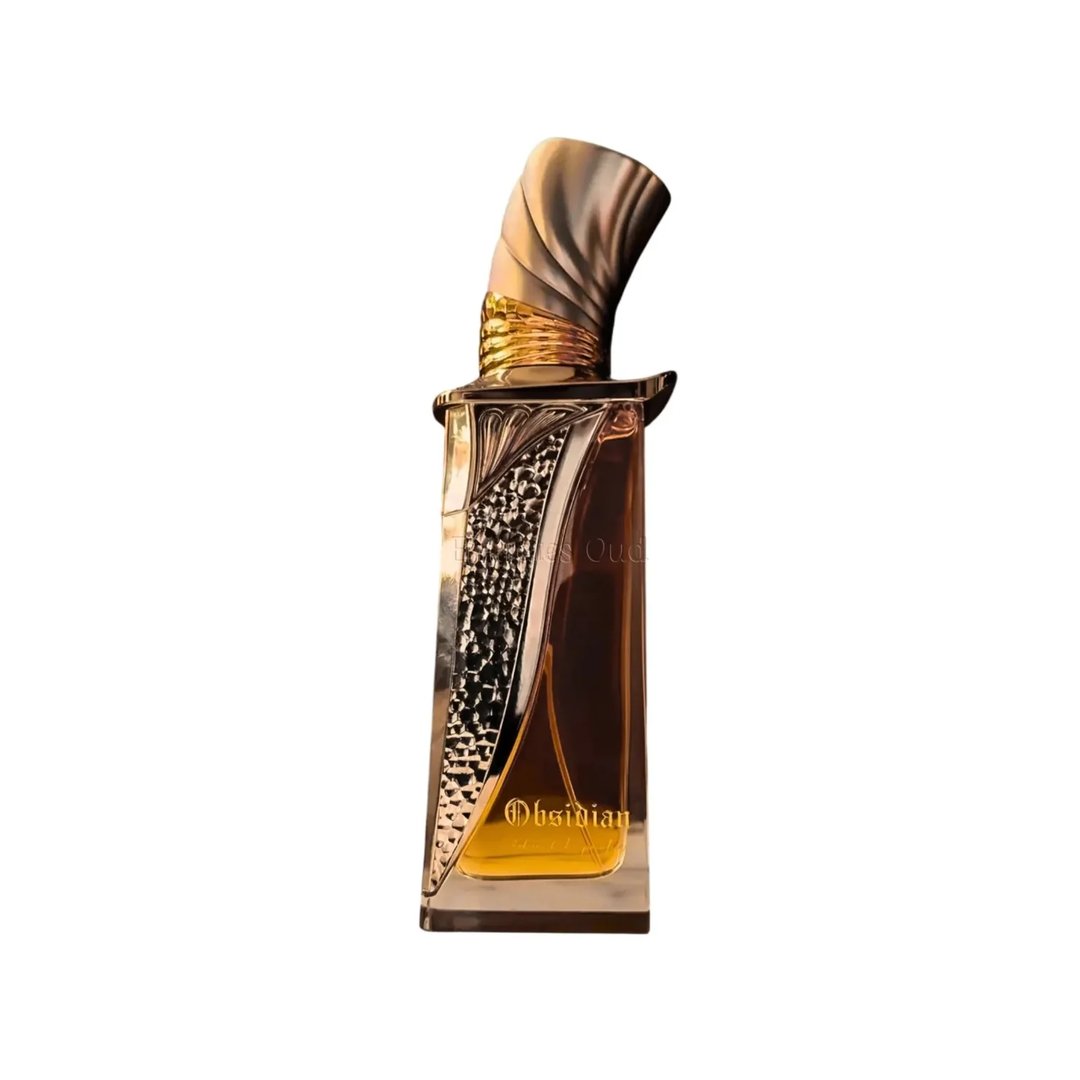French Avenue Obsidian French Avenue Eau De Parfum 100ml Unisex — Tall rectangular glass bottle with golden ornate detailing and a curved, textured gold cap, filled with amber liquid.