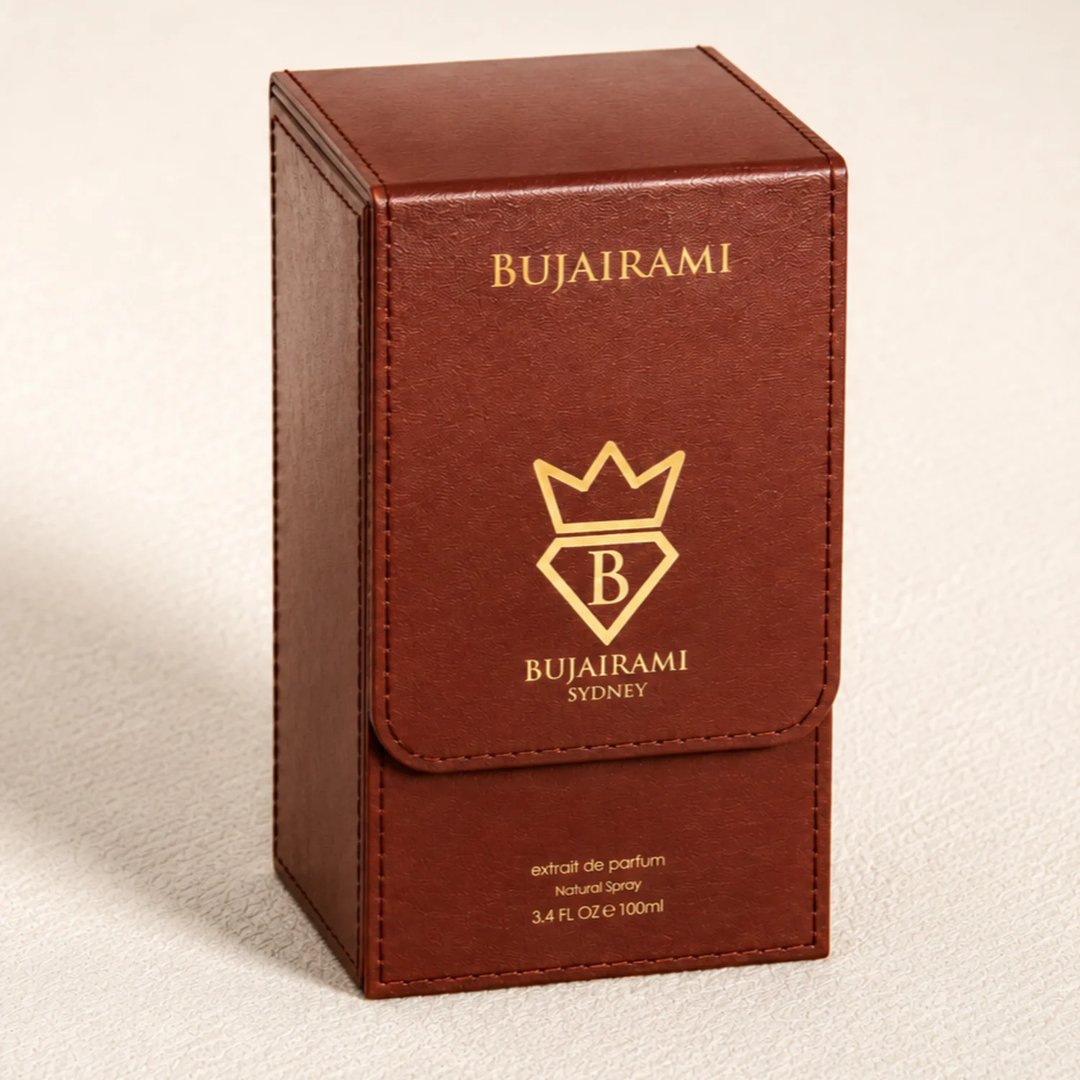 Bujairami Oud Money by Bujairami 100ml Extrait — A brown leather-like box for perfume, featuring gold embossed branding and a crown logo with a 'B' inside a diamond.