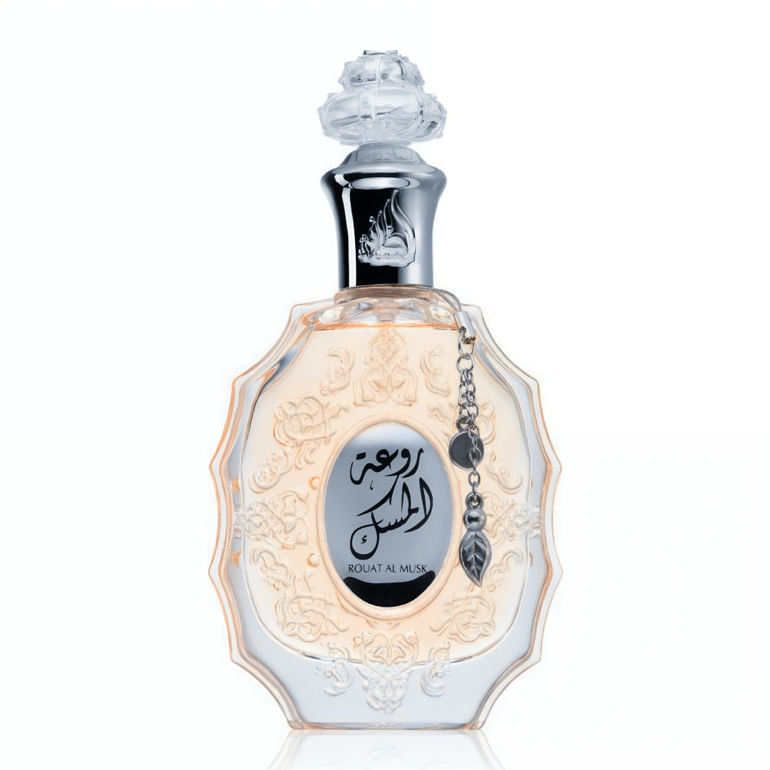 Lattafa Rouat Al Musk by Lattafa 100ml for Women — Clear glass perfume bottle with ornate embossed detailing and a silver chain with a leaf charm hanging from the neck, featuring Arabic script and 'ROUAT AL MUSK' text on the front label.
