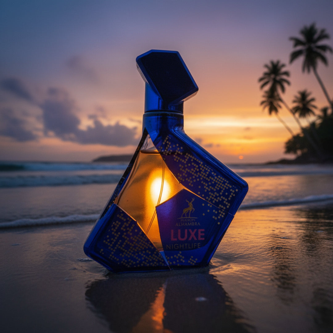 Maison Alhambra Luxe Nightlife by Maison Alhambra Unisex 100 ml — Blue geometric bottle with gold accents on a wet sandy beach at sunset, with palm trees and ocean waves in the background.