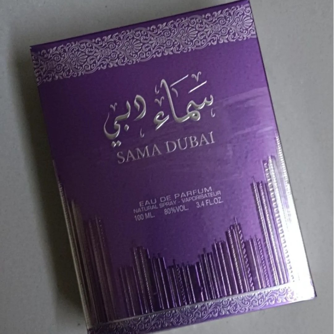 Ard Al Zaafaran Sama Dubai 100ml — A purple perfume box with silver Arabic calligraphy and text "SAMA DUBAI" in English, featuring a cityscape silhouette at the bottom. | Ard Al Zaafaran Sama Dubai 100ml — Kotak minyak wangi ungu dengan kaligrafi Arab perak dan teks "SAMA DUBAI" dalam bahasa Inggeris, menampilkan