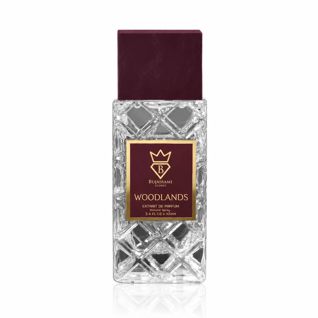 Bujairami Woodlands Extrait de Parfum 100ml — Clear faceted glass bottle with a deep maroon cap, featuring a gold-bordered maroon label with a crown and 'B' logo.